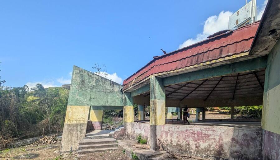 The side of the old church: an open-sided building with a red roof and walls painted green, gold, and red